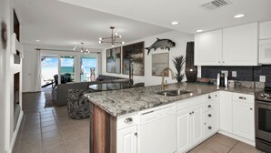 A modern kitchen with white cabinets, a granite countertop, and a large fish mural. - Oceanfront, stunning, renovated, Guests love it! (Ponte Vedra Beach)