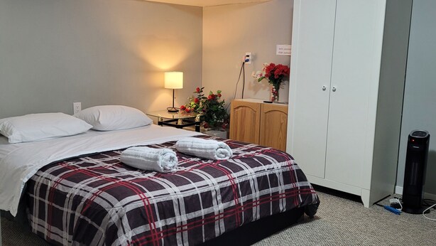 Habitación de hotel con una cama, una mesita de noche con lámpara, un armario y un ventilador.