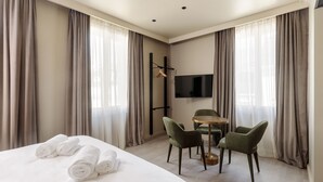Een hotelkamer met een bed, twee stoelen, een tafel en een televisie.