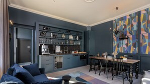 Een moderne keuken met inbouwapparatuur, een eethoek met een houten tafel en stoelen, en een blauwe accentmuur.