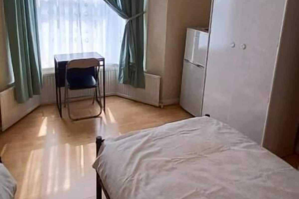 Una habitación con cama, una silla, armario y radiador.