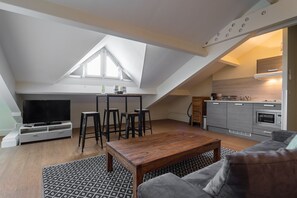 Un espacio habitable estilo loft con comedor, cocina y televisor.