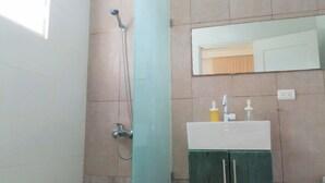 Un baño con ducha, lavamanos y espejo.