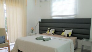 Un dormitorio con una cama grande, una mesita de noche, una silla y una ventana con persianas.