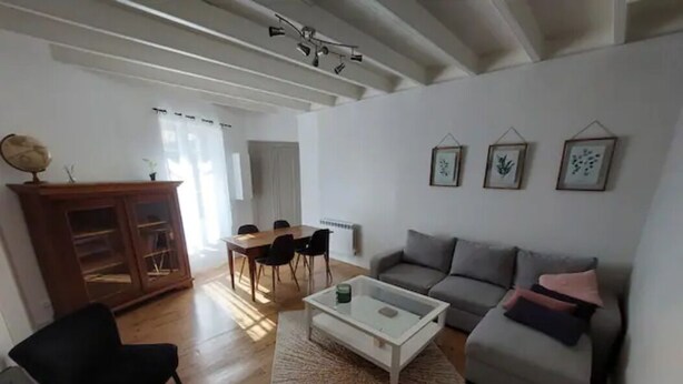 A living room with a sofa, armchair, coffee table, and a dining area with chairs and a table. - La Maisonnette du Marais - 1 à 6 Pers (Doix lès Fontaines)