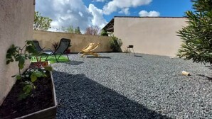 A patio area with a gravel surface, two lounge chairs, a small table, and potted plants. - La Maisonnette du Marais - 1 à 6 Pers (Doix lès Fontaines)
