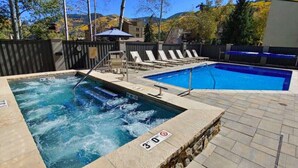 A swimming pool with a hot tub, lounge chairs, and a stone border. - Recently remodeled 3bdr condo in Lionshead (Vail)