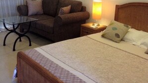 Une chambre d’hôtel avec un lit, un canapé, une petite table et une lampe.