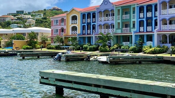 Una propiedad frente al agua con edificios coloridos, un muelle y barcos.
