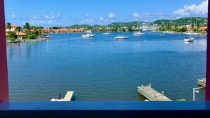 Un puerto deportivo con varias embarcaciones amarradas, un cielo azul despejado y vistas del paisaje circundante.
