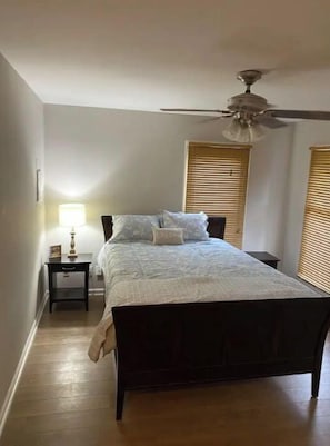 Cozy retreat with a dark bed frame, white quilted bedspread, and a bedside table with a lamp.