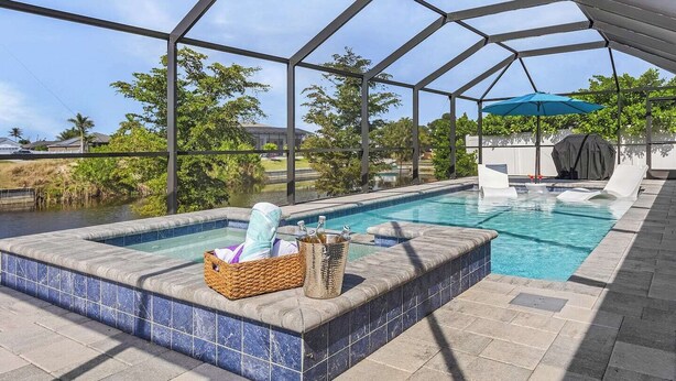 Een overdekt buitenzwembad met een jacuzzi, ligbedden en een pergola.