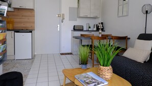 A compact living space with a kitchenette, a dining area, and a seating area with a sofa and a coffee table. - T2 apartment with garden and parking, ROYAN, near seafront (Royan)