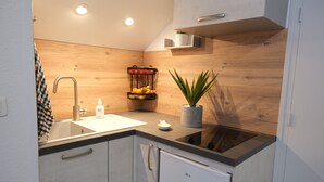 A modern kitchen with a black countertop, white cabinets, a stainless steel sink, and a built-in oven. - T2 apartment with garden and parking, ROYAN, near seafront (Royan)
