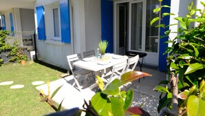 An outdoor patio with a table set for dining, surrounded by chairs. - T2 apartment with garden and parking, ROYAN, near seafront (Royan)