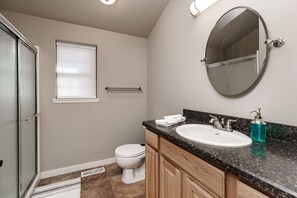 A modern bathroom with a toilet, sink, and mirror. - Cowboy Cabin on Cooper (Red Lodge)