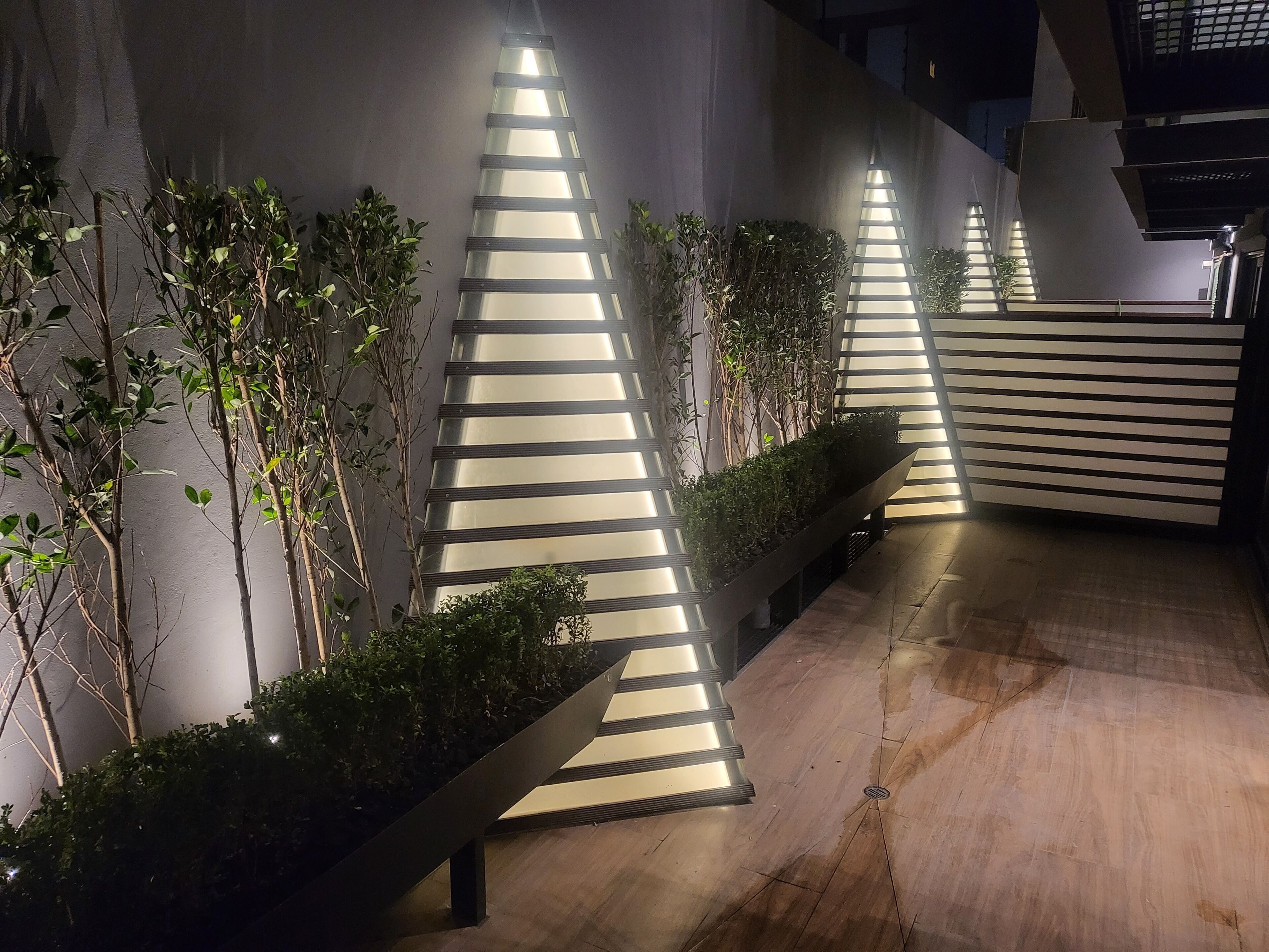 Un espacio exterior moderno con lámparas geométricas y macetas.