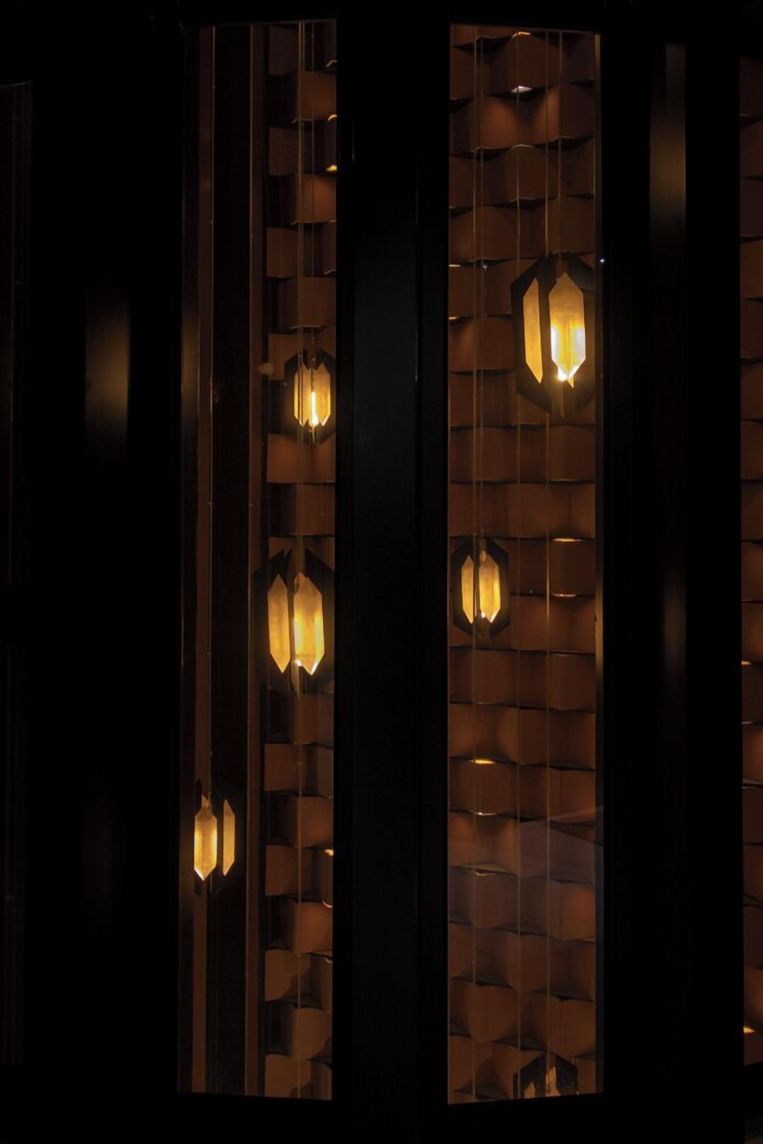 Um interior escuro com arandelas iluminadas e um desenho de parede estampado.
