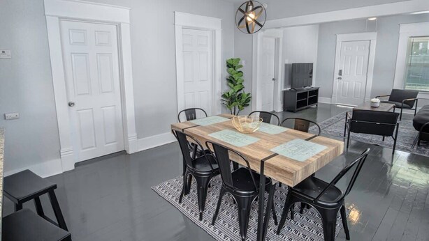Un coin repas avec une table en bois, des chaises noires et un luminaire suspendu.