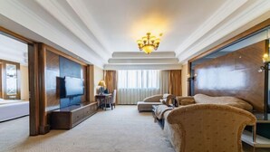 A spacious hotel room with a large bed, a seating area with sofas, a television, and a chandelier. - Tianma Hotel (Shantou)