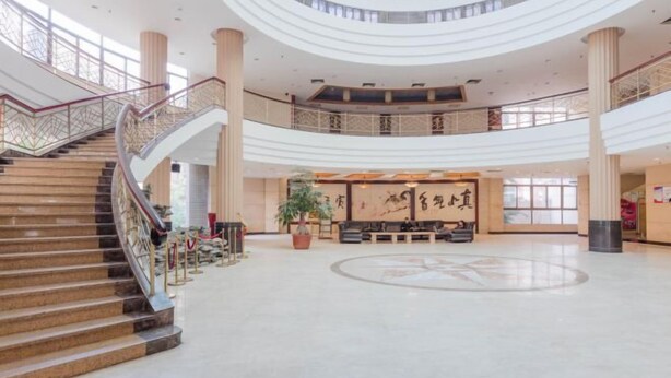 A spacious lobby with a central seating area, a staircase, and a large column. - Tianma Hotel (Shantou)