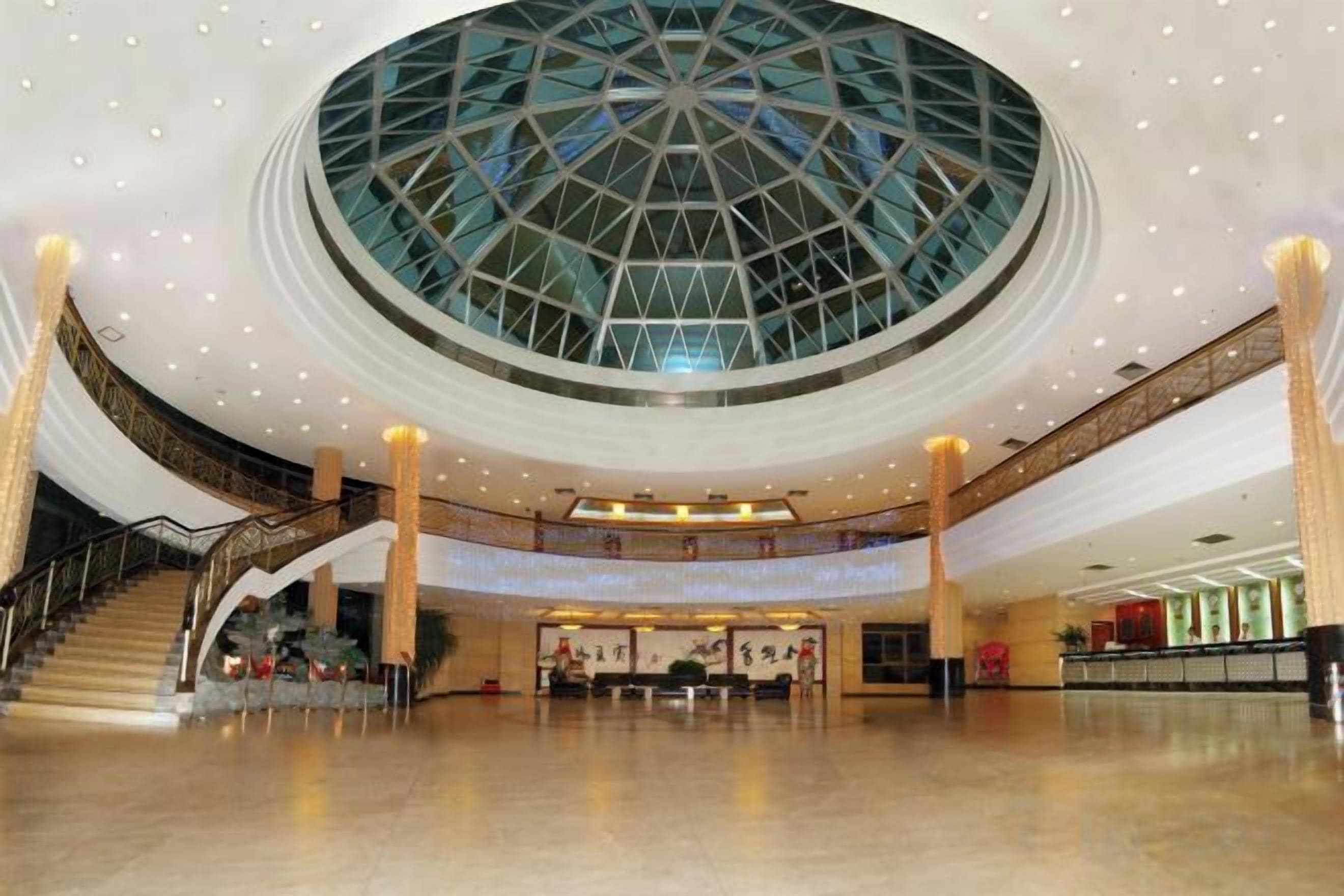 A spacious lobby with a central glass dome ceiling, a staircase, and a reception area.