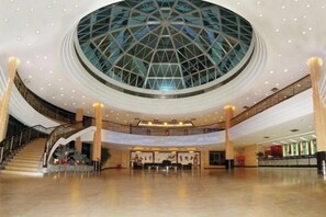 A spacious lobby with a central glass dome ceiling, a staircase, and a reception area. - Tianma Hotel (Shantou)