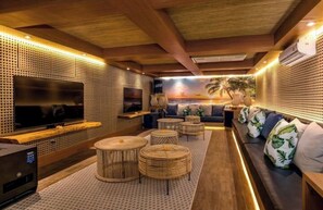 Relax in style with a comfortable lounge area featuring a large flat-screen TV, sofa, and casual dining space.