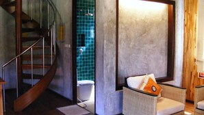 Ein Zimmer mit einer Wendeltreppe, einer Sitzecke mit Kissen und einer Fliesenwand.