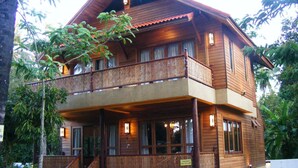 Ein zweistöckiges Holzhaus mit Balkon, Veranda und einem Schild, das anzeigt, dass es vermietet wird.