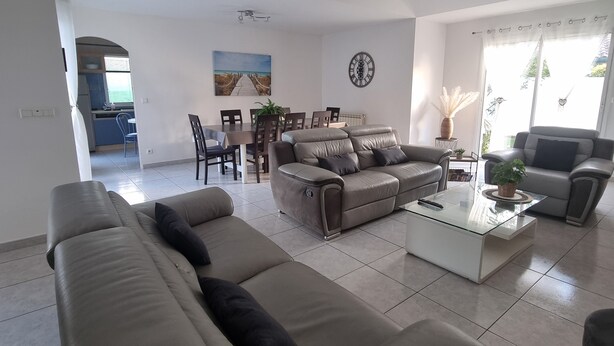 Ein geräumiges Wohnzimmer mit einer Couch, einem Couchtisch und einem Essbereich mit Stühlen und einem Tisch.
