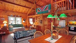 A cozy log cabin interior with a dining area, kitchen, and living room. - Poconos Log Cabin Getaway (Lehighton)