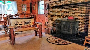 Cozy cabin-style room features a traditional fireplace with a brick surround and a wooden bench.