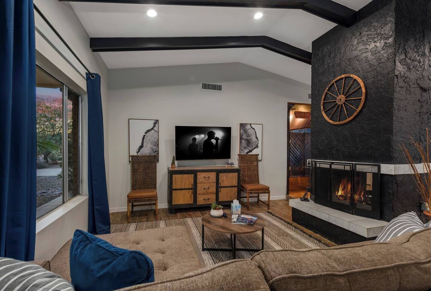 A modern living room with a fireplace, a television, and a large window with curtains.
