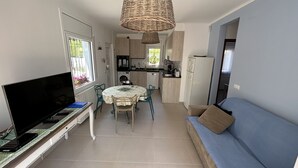 A compact living space with a TV, dining table, and sofa. - Charming, renovated house—4-minute walk to Grifeu Beach—Beautiful garden—Parking—Air conditioning (Llançà)