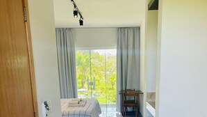 Une chambre d’hôtel avec un lit, un bureau et une vue sur la verdure.