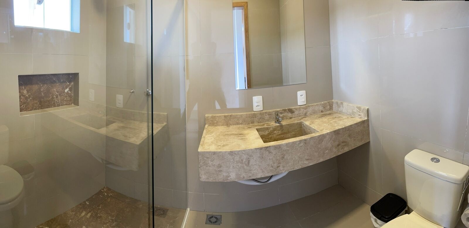 A modern bathroom with a glass-enclosed shower, a marble sink, and a toilet.