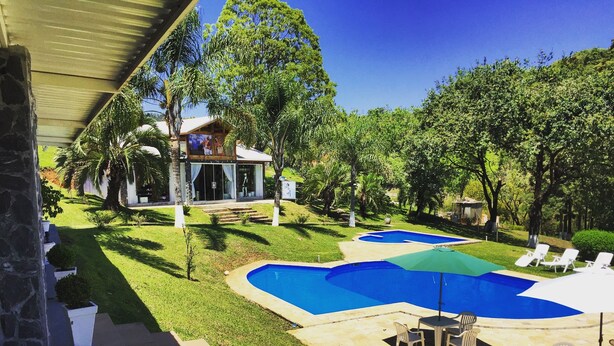 Un jardin avec une piscine, un espace salon extérieur et une maison dotée d’un patio couvert.