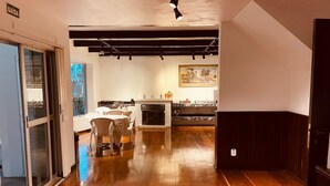 Un vaste espace de vie doté d’un plancher en bois, d’une table à manger avec des chaises, d’une cheminée et d’un coin cuisine avec un comptoir en marbre.