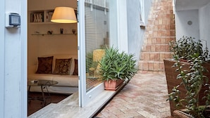 A modern outdoor space with a sliding glass door leading to a living area, a potted plant, and a brick staircase. - Villa Lux with Swimming Pool (Sorrento)