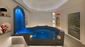 A modern spa area with a hot tub, a skylight, and a decorative wall with a crown emblem. - Villa Lux with Swimming Pool (Sorrento)