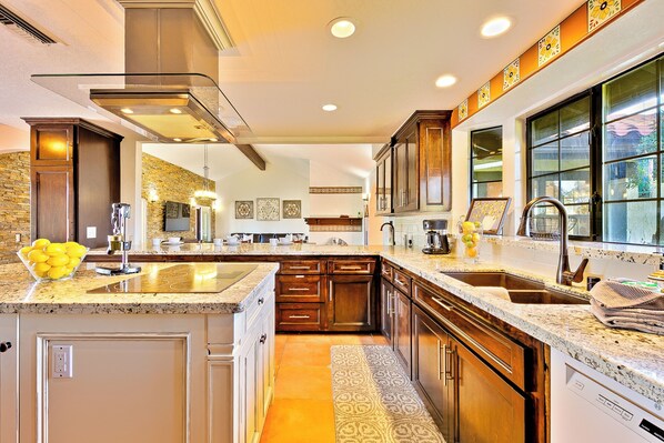 A modern kitchen with granite countertops, stainless steel appliances, and wooden cabinetry.