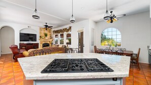 Un espacio habitable espacioso con una isla cocina grande, una chimenea y un comedor con vistas al exterior.