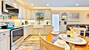 A modern kitchen with white cabinetry, a built-in oven, and a dining area with a wooden table and chairs. - 25% Off Sept WkDay, Near Wineries -Private Jacuzzi (Temecula)