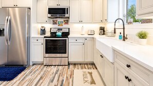 A modern kitchen with white cabinetry, stainless steel appliances, and a patterned floor rug. - 25% Off Sept WkDay, Near Wineries -Private Jacuzzi (Temecula)