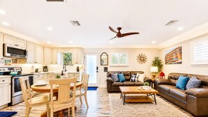 A modern living room with a brown leather sofa, a dining table with chairs, a kitchen with white cabinets, and a ceiling fan. - 25% Off Sept WkDay, Near Wineries -Private Jacuzzi (Temecula)