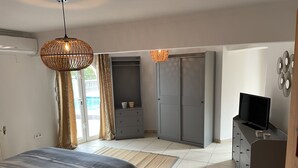 Un dormitorio con cama, televisor, armario y escritorio.