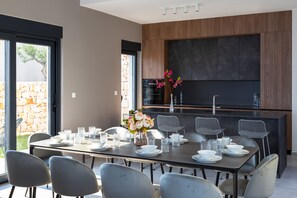 Un espace repas moderne avec une grande table dressée pour six personnes, entourée de chaises grises.