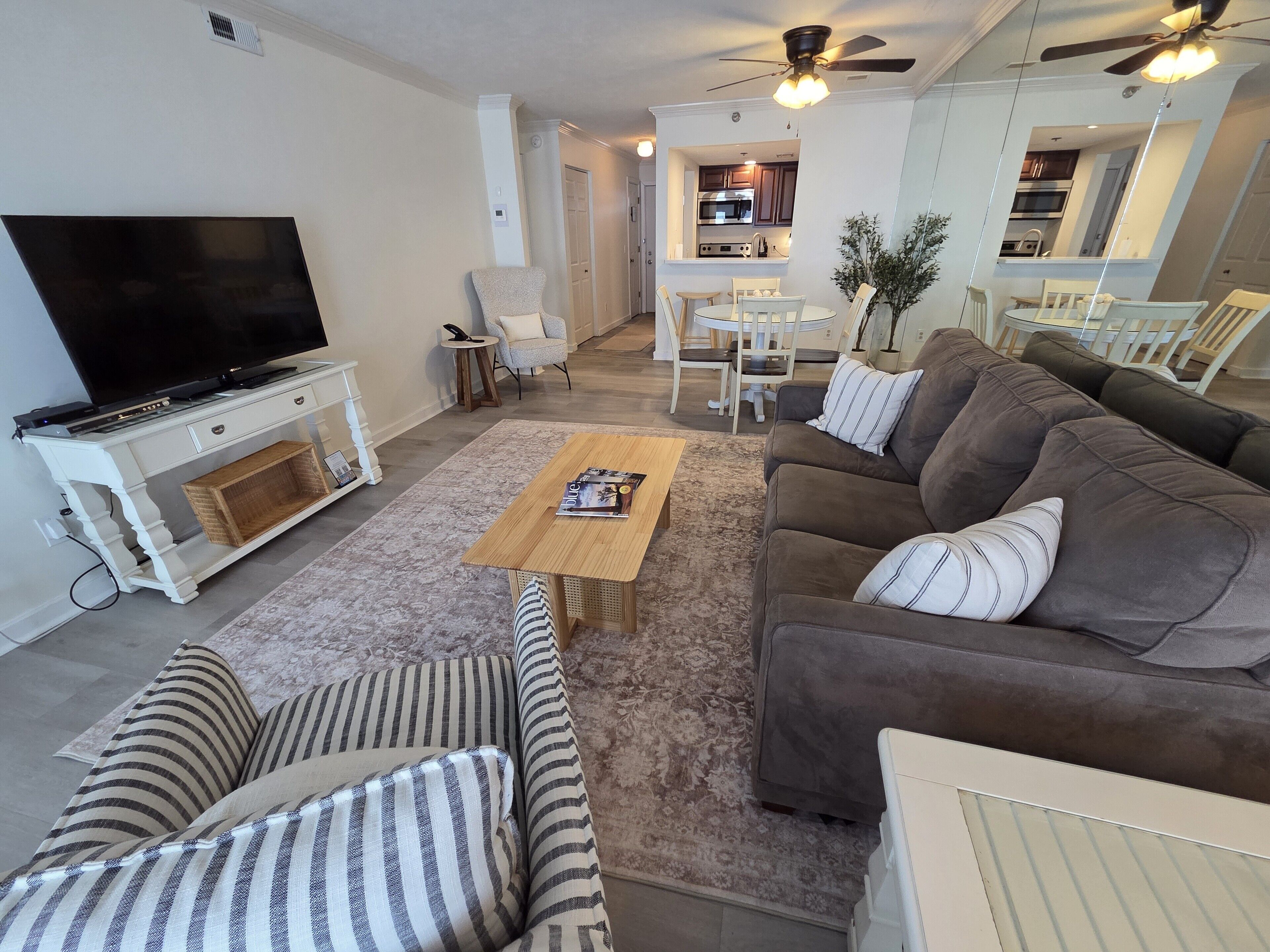A living room with a TV, sofa, coffee table, and striped cushions.