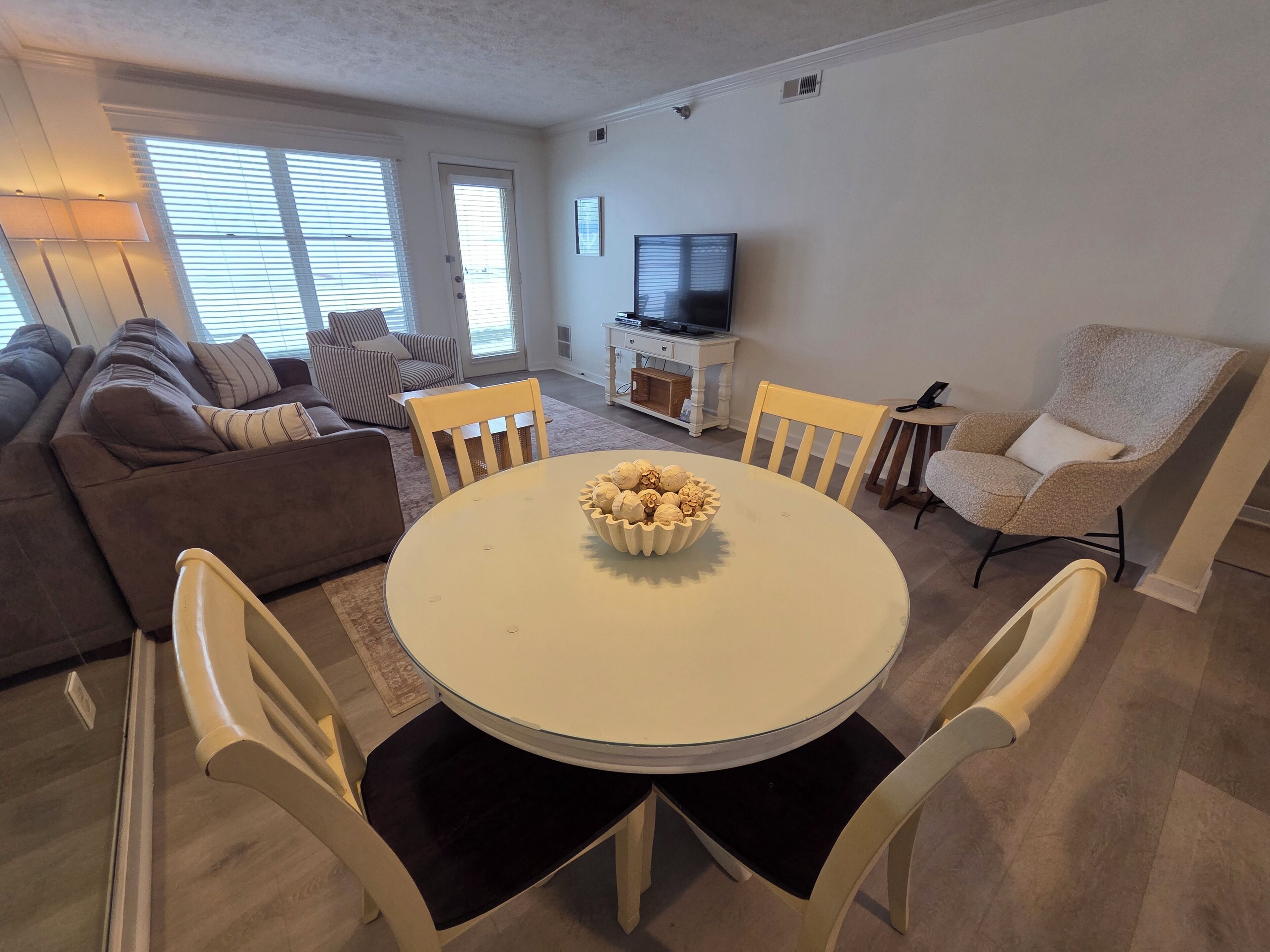 A living room with a round table, chairs, a sofa, and a television.
